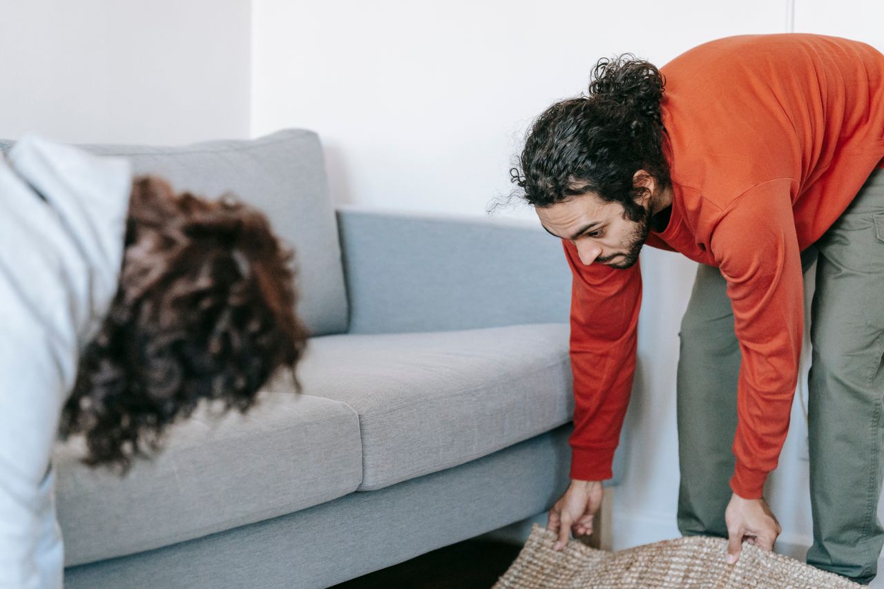 why-choose-us A pair straightening up their living room, arranging furniture and rugs together as a team.